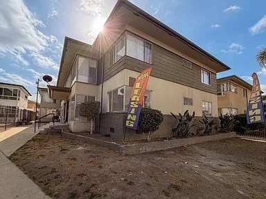 A sunny day at a home for sale with a sign in front.