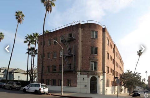 A red brick building with a white car parked in front.
