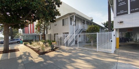 A white building with a gate in front of it.