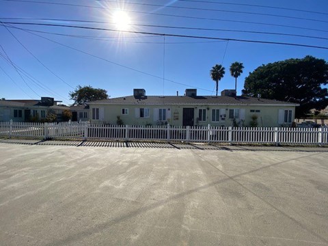 A house with a fence in front of it on a sunny day.