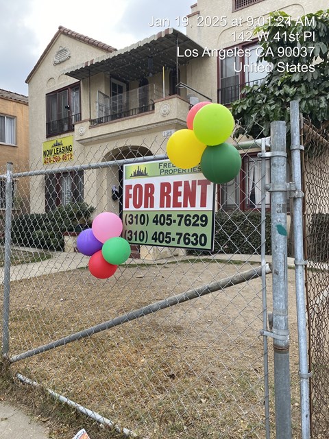 A house with a fence and a sign that says "FOR RENT" in front of it.