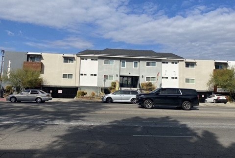 A black car is parked in front of a white building.