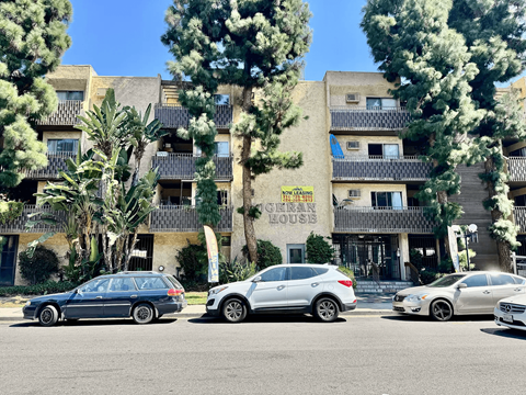 A row of cars parked in front of a building with a sign that says "House".
