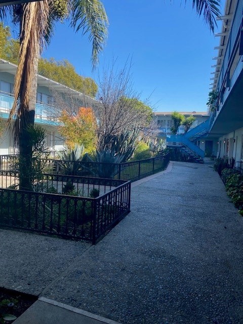 A tree-lined walkway leads to a building.