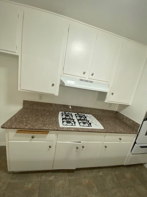 A kitchen with white cabinets and a granite countertop.