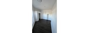 A room with white walls and dark wood flooring.