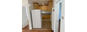 A kitchen with a white refrigerator and wooden cabinets.