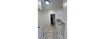 A kitchen with white cabinets and a tiled floor.