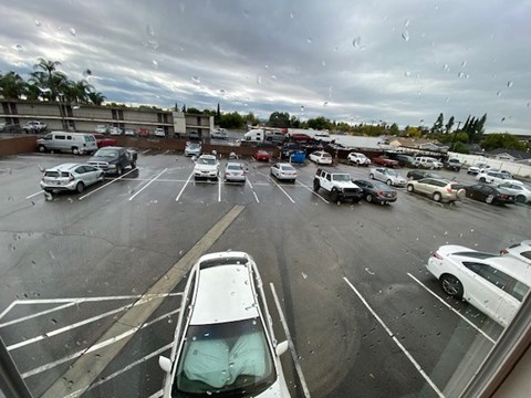 A parking lot with cars and a cloudy sky.