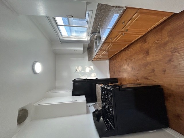 A black computer case sits on a white desk in a room with a skylight.