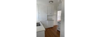 A kitchen with white cabinets and a white refrigerator.