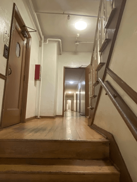 A long hallway with a staircase on the right and a door on the left.
