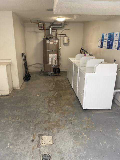 A dirty utility room with a water heater and a washer and dryer.