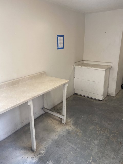A white desk and a white dresser are in a room with a blue paper on the wall.