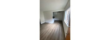 A room with wooden flooring and a window on the right side.
