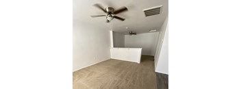 A room with a ceiling fan and a smaller fan on the wall.
