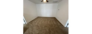 A room with a carpeted floor and a ceiling fan.