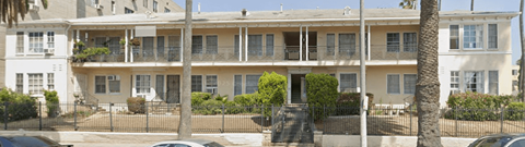 A white building with a balcony and a black fence.