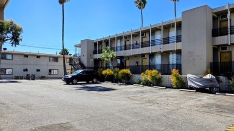 A black car is parked in front of a building with a white car parked in front of a smaller building.