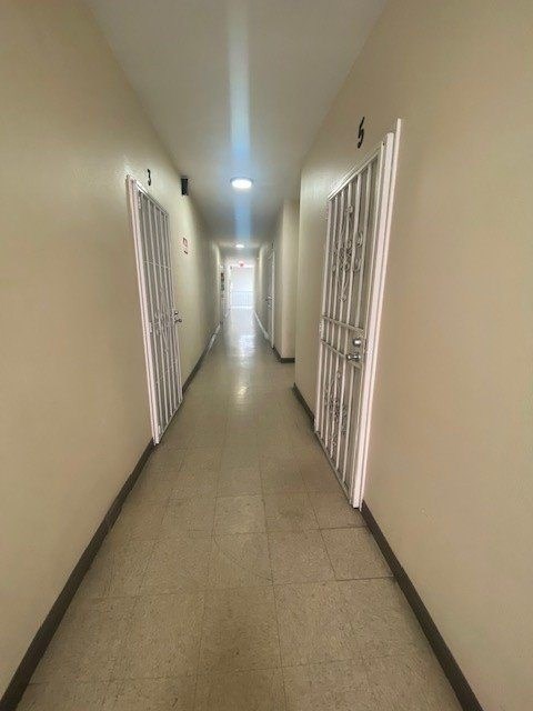 A long hallway with doors on both sides and a light at the end.