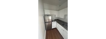 A kitchen with white cabinets and a stainless steel refrigerator.