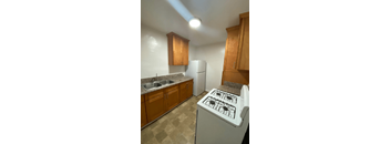 A kitchen with a white stove top oven and wooden cabinets.