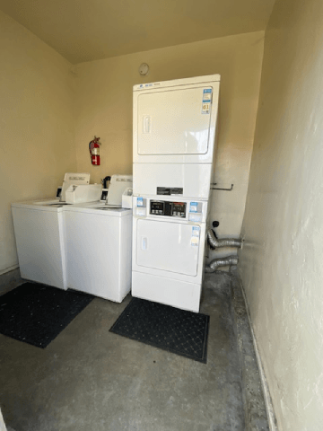 A white refrigerator and washing machine in a small room.