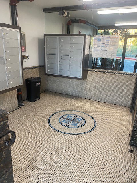 A room with a mosaic floor and a trash can.