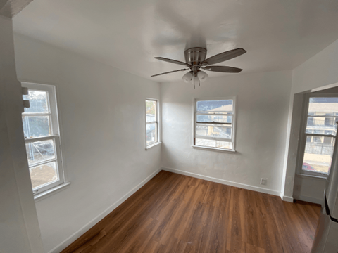 A room with a ceiling fan and wooden floors.