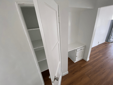 A white door is open to a room with a white cabinet and drawers.