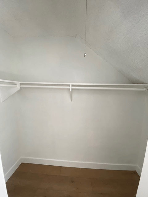 A white wall with a wooden floor and a white ceiling.