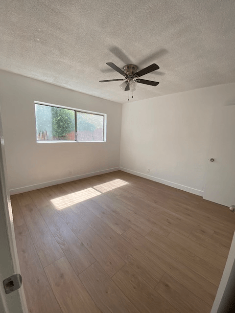 A room with a ceiling fan and a window.