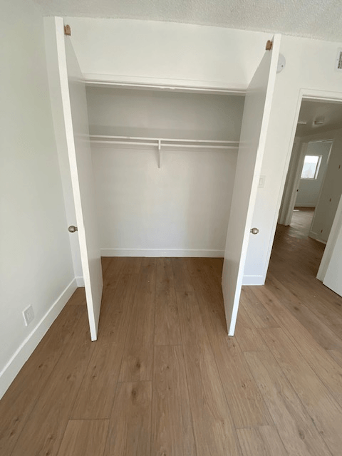 A room with a white door and a wooden floor.