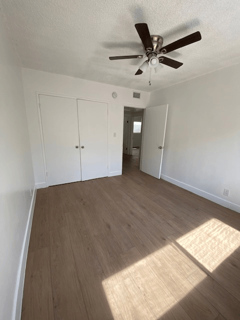 A room with a ceiling fan and wood flooring.