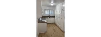 A kitchen with white cabinets and a brown countertop.