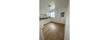A kitchen with white cabinets and a wooden floor.