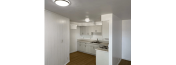 A kitchen with white cabinets and a wooden floor.