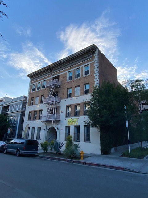 A building with a sign that says "For Rent" is on the corner of a street.