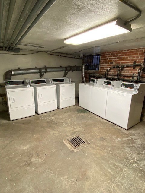 A row of white washing machines in a basement.