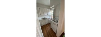 A kitchen with white cabinets and a white stove.