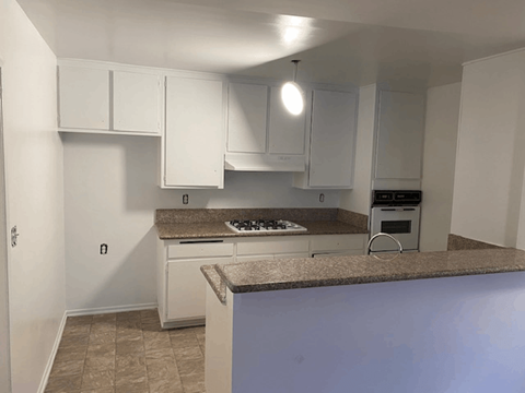 A kitchen with white cabinets and a granite countertop.