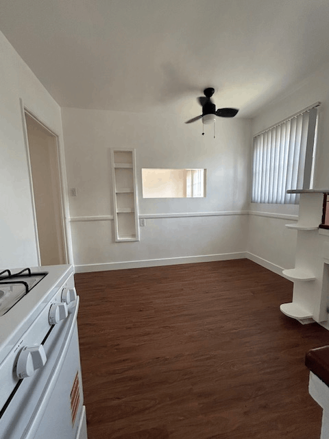 A white stove in a room with wooden floors and a window.