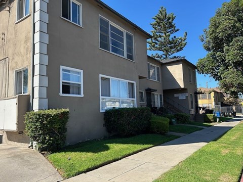 A beige apartment building with a green lawn in front.