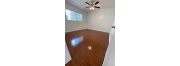 A room with a ceiling fan and wooden flooring.