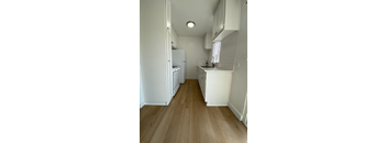 A kitchen with white appliances and wooden floors.