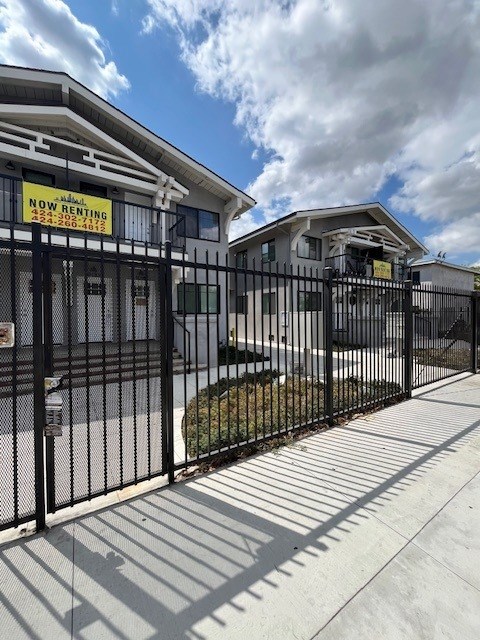 A fence surrounds a building with a sign that says "NOW RENTING".