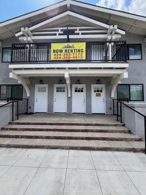 A two-story building with a balcony and a sign that says "NOW RENTING" is for sale.