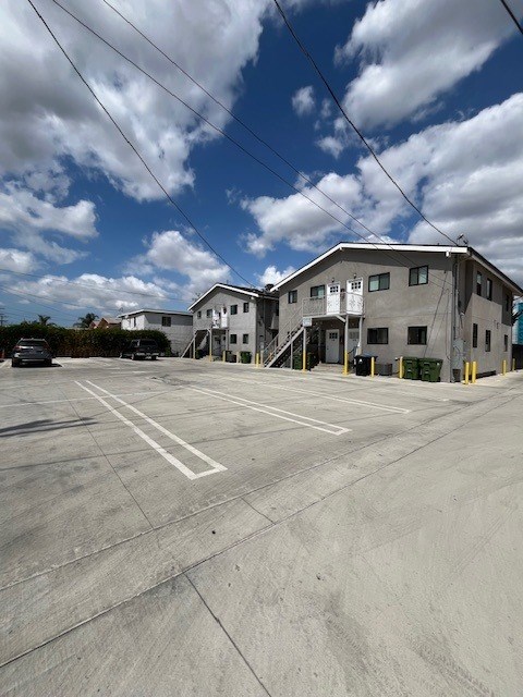 A large grey building with a parking lot in front.