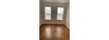 A room with wooden floors and two windows.