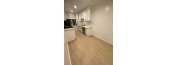 A kitchen with white cabinets and a wooden floor.